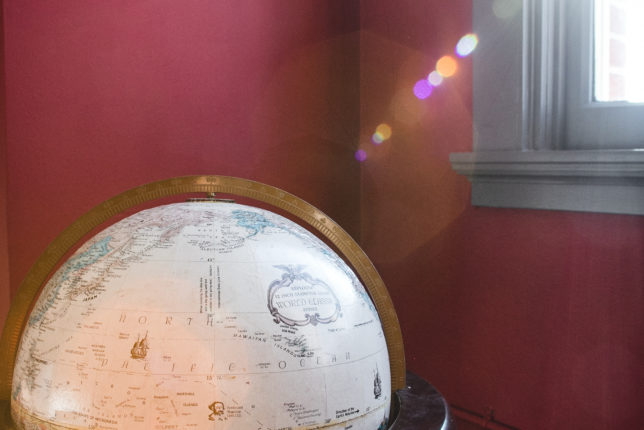 A globe and sunlight in front of the dark red walls at The Sunset Room