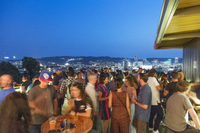 A busy night on the roof deck at Revolution Hall, with the Portland skyline in the background.