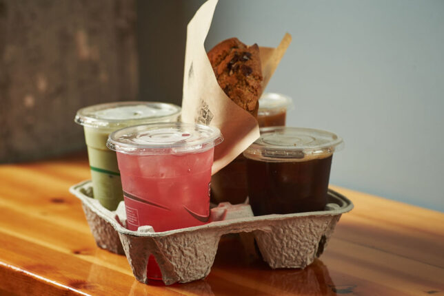 A selection of drinks from Martha's cafe in a carry-out tray, with a baguette sandwich in the middle